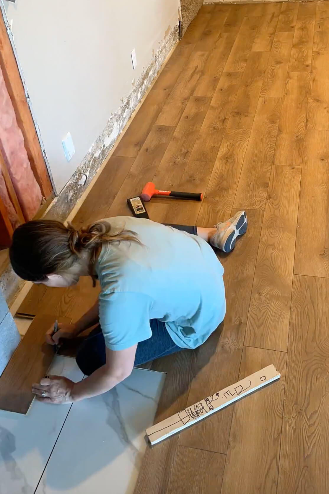 Cutting laminate flooring to fit against an edge.